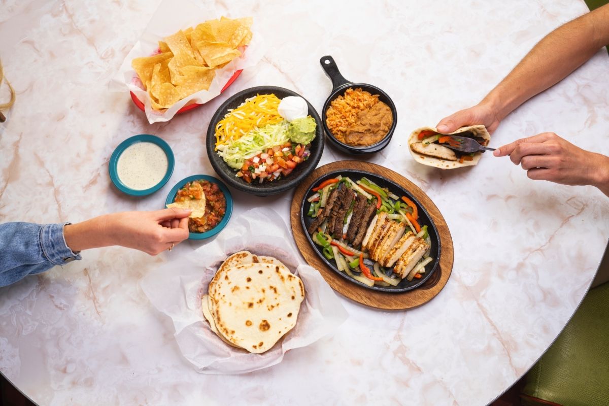 Table of fajitas with two people making their own custom plates