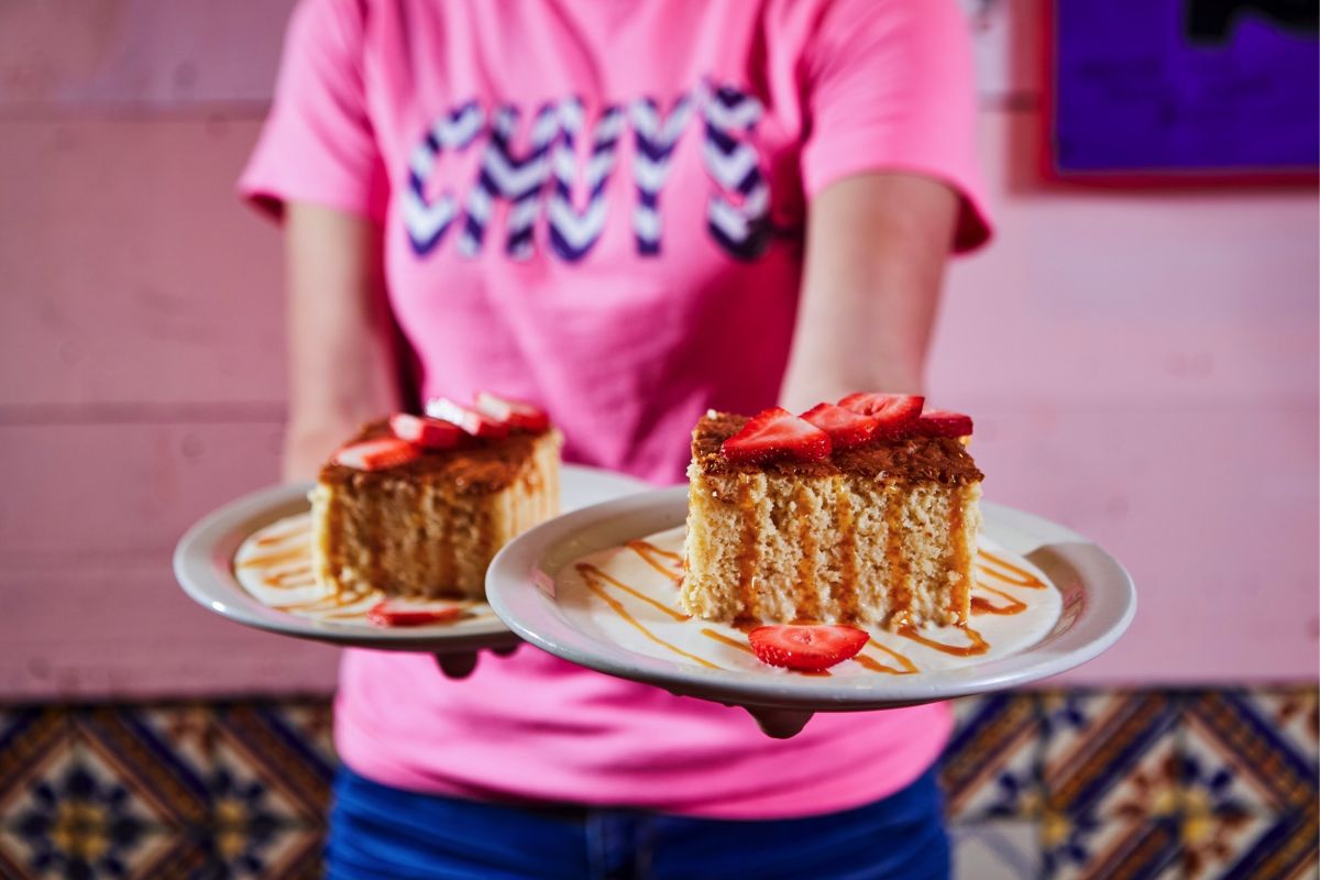 A server bringing out two plates of our moist and sweet tres leches.