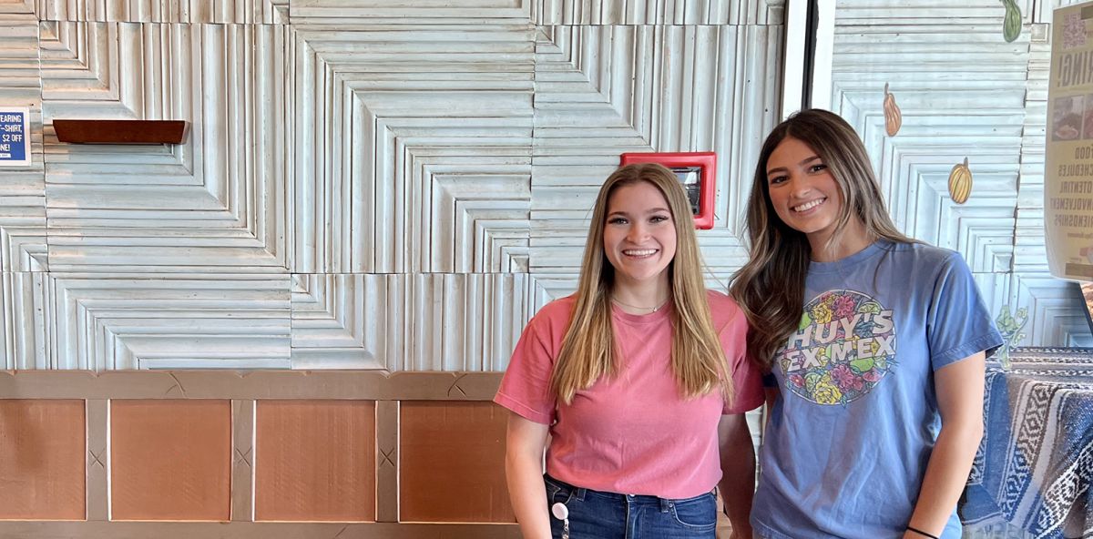 Two employees posing for a picture in their office.