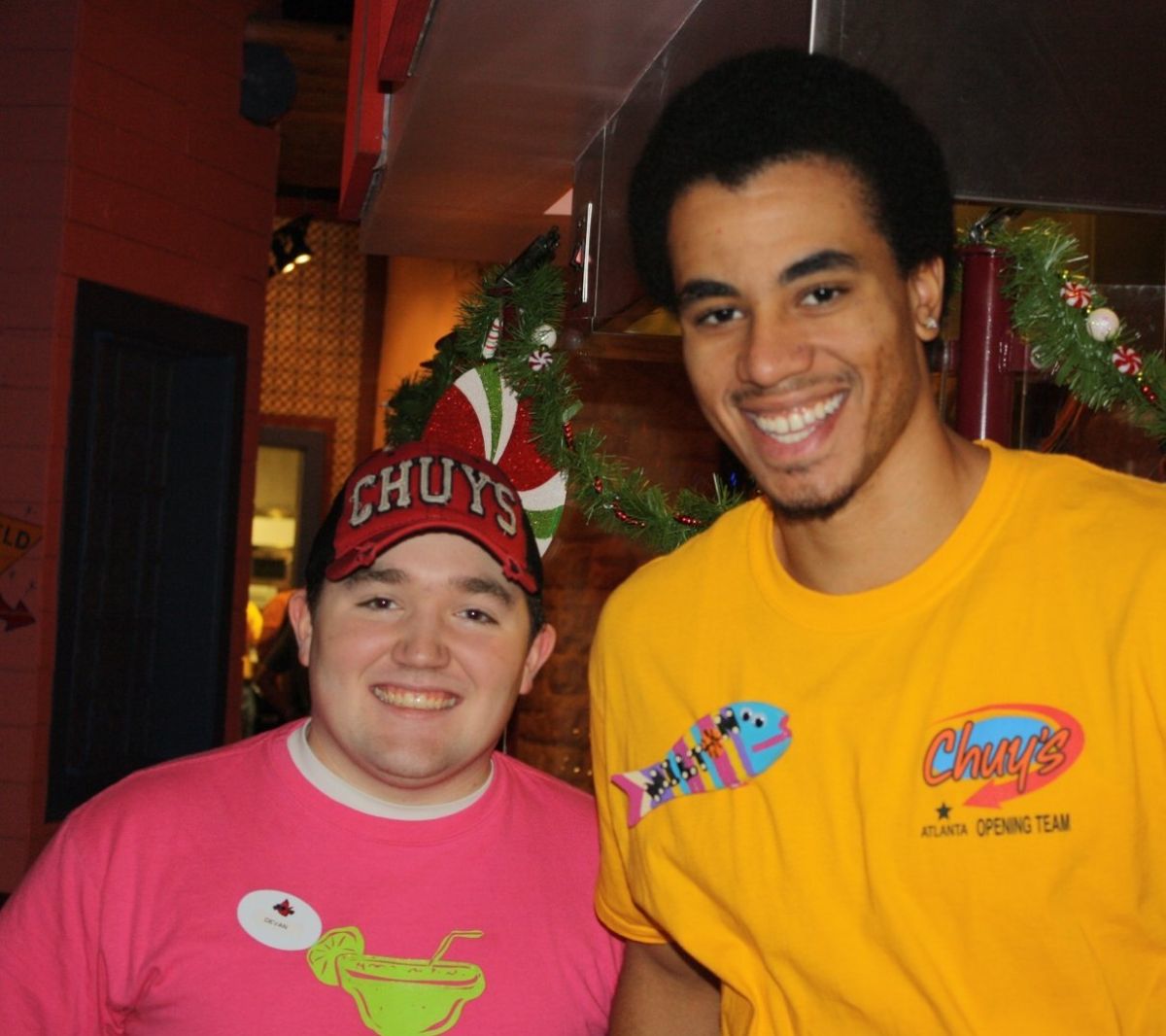 Two very happy Chuy’s employees standing in front of some Christmas decorations